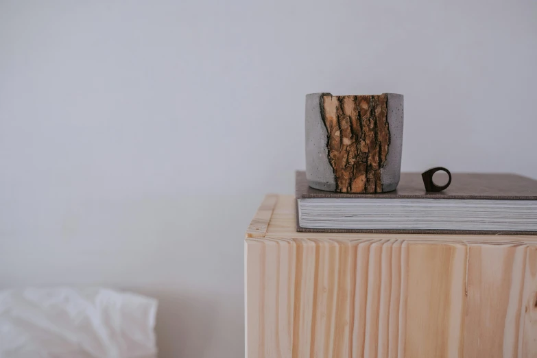 a wooden table topped with a book and a vase