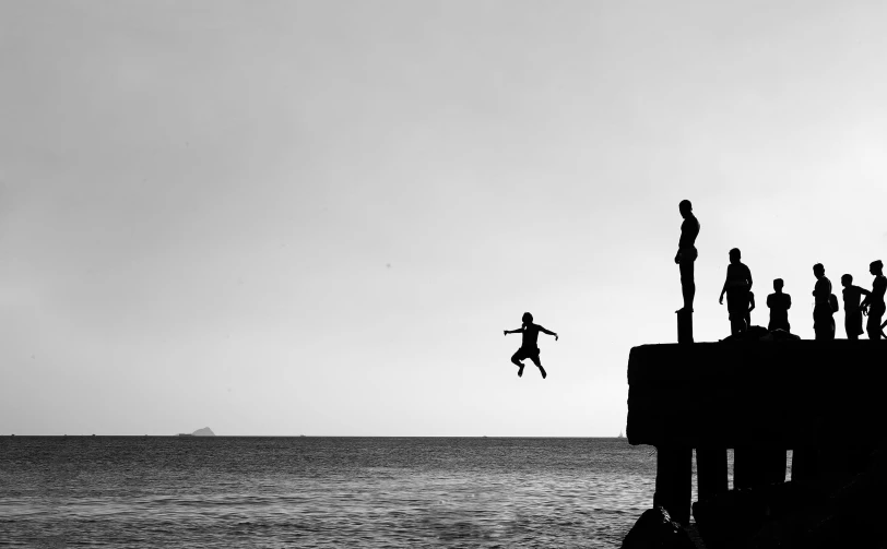 black and white po of a person jumping off a pier