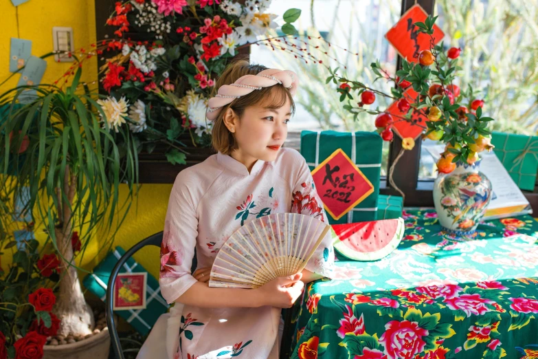 a  is sitting at a table holding a fan