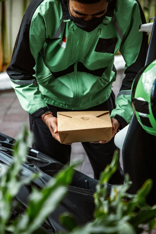 a person in a green jacket stands over a box