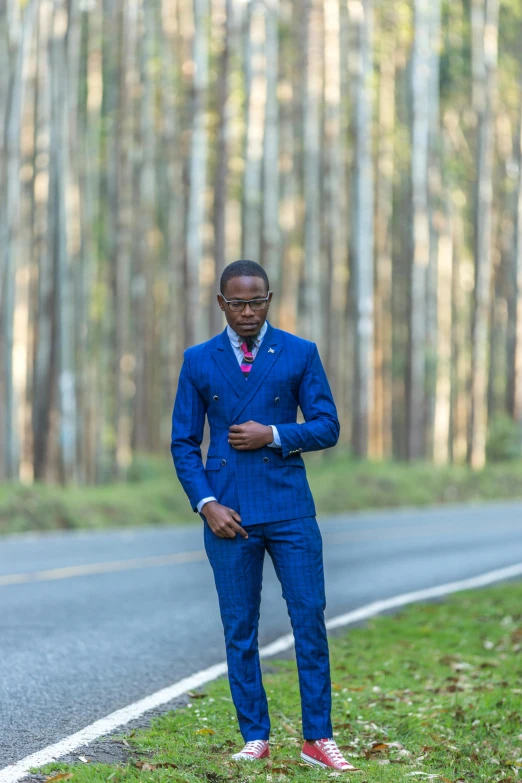 a man is standing next to a grassy hill in a suit