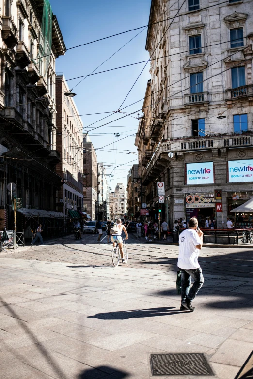 two people riding bikes and skateboarding on a city street