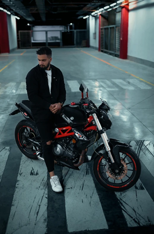 man with foot and bag siting on a motorcycle in parking garage