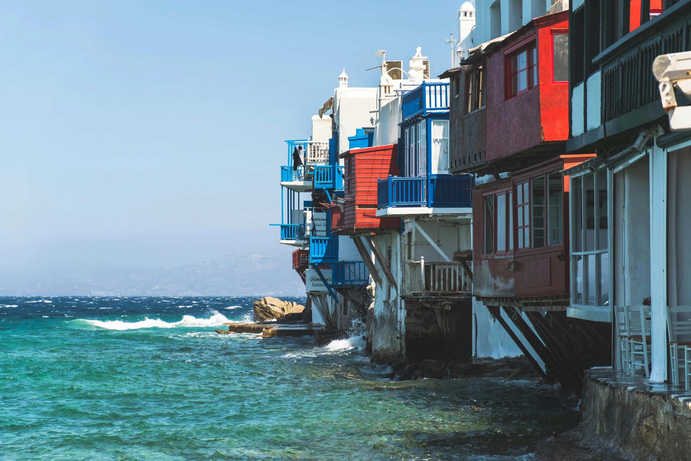 several colorful buildings line a water filled street with a boat in the ocean