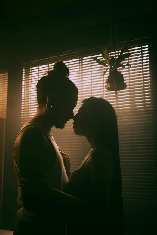 two people are standing by the window with blinds