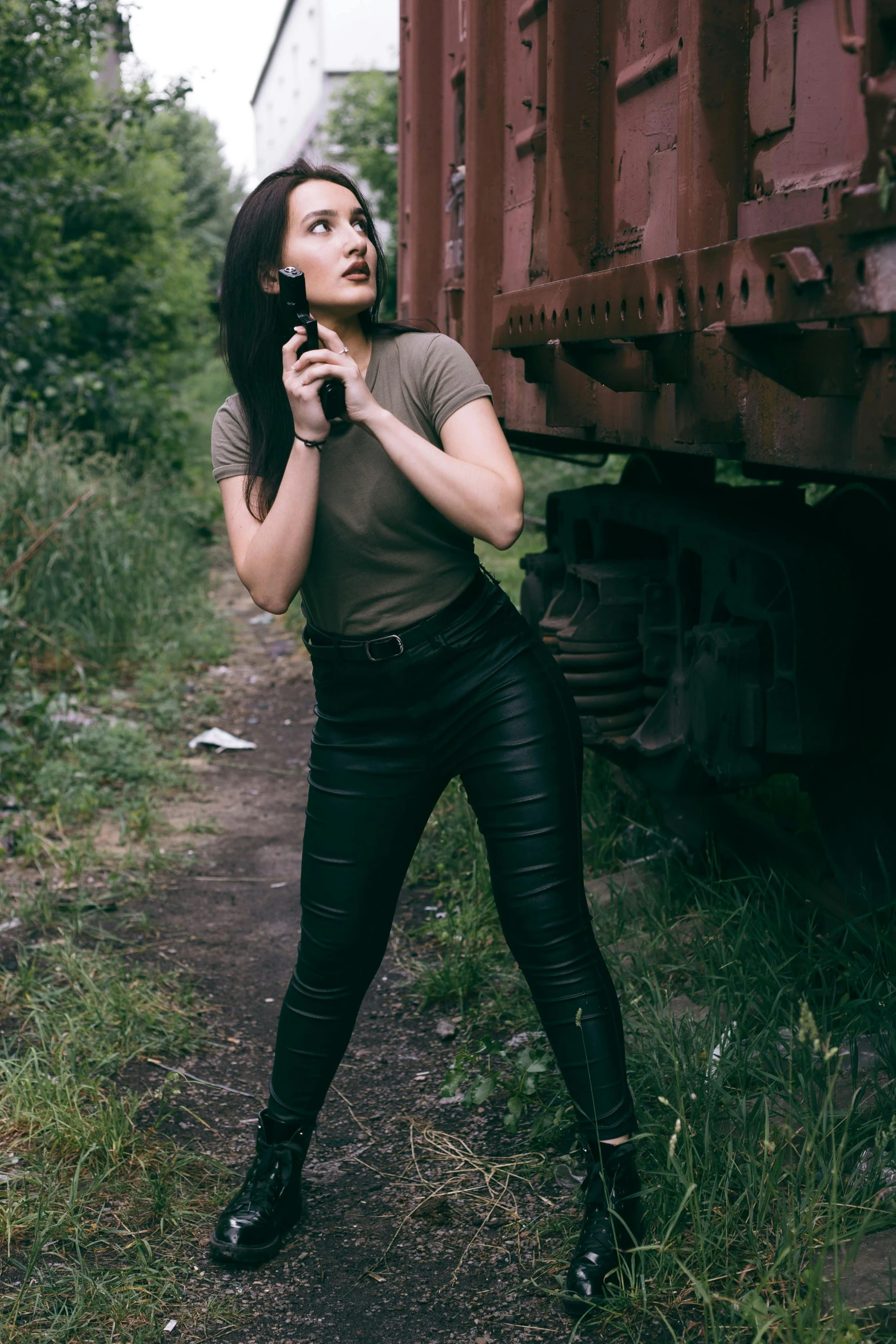 a woman poses near an old train car in leathers