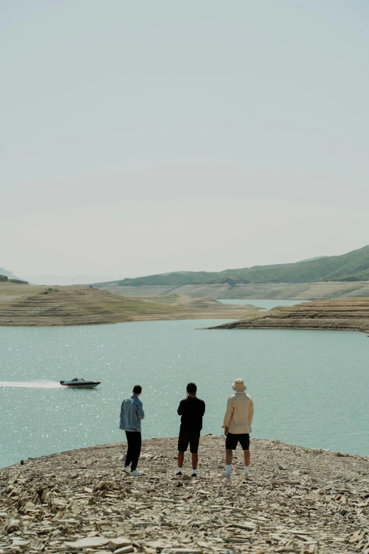 three men standing on a beach next to the ocean