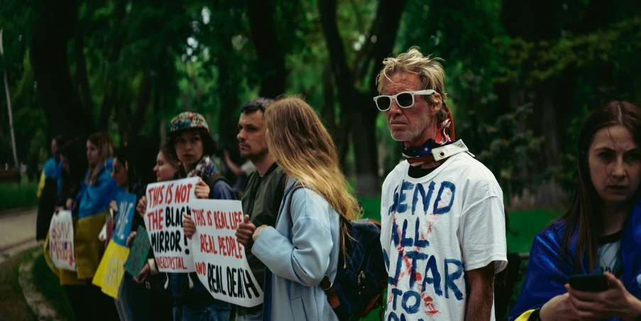 people stand in a line with signs and phones