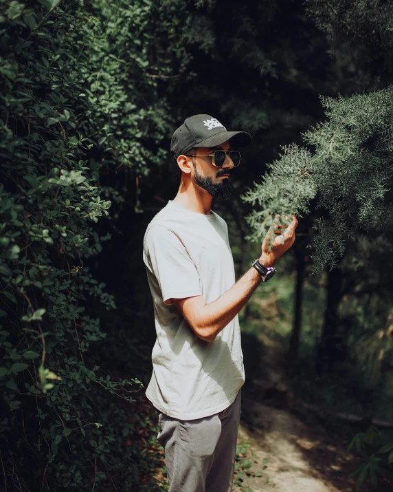 a man in a hat and sunglasses holds up plants