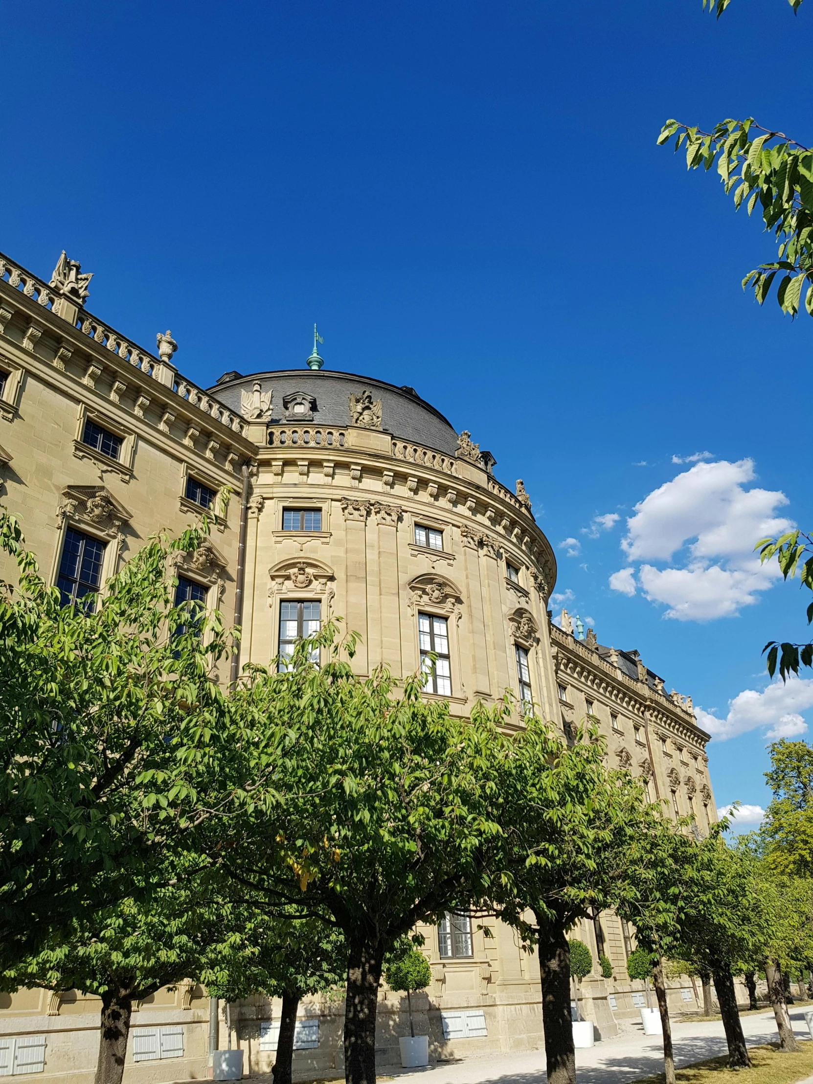 the large brown building has several trees in front of it