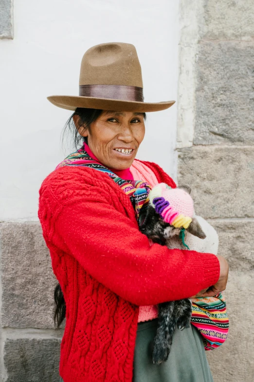 a woman wearing a hat holding a baby sheep