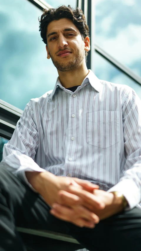 a man sitting in a chair wearing a white shirt