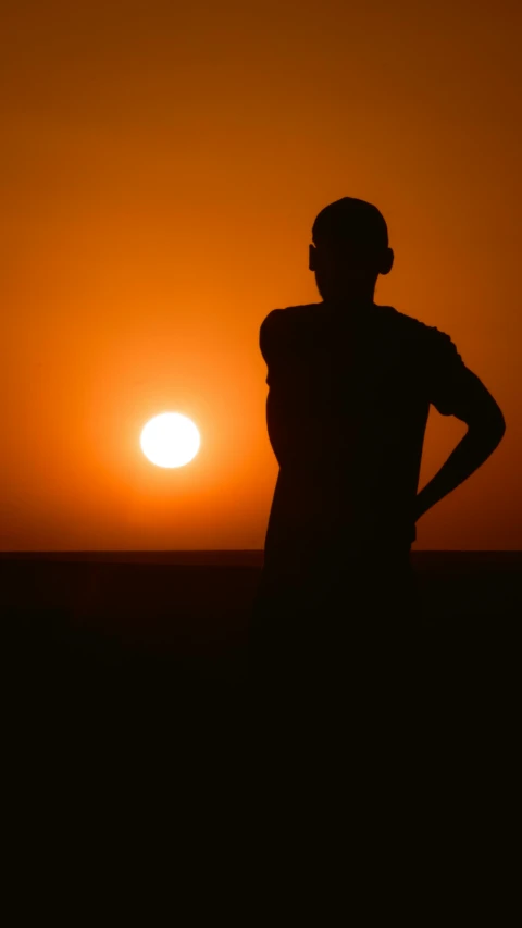 a black and white silhouette of the sun rising behind a man