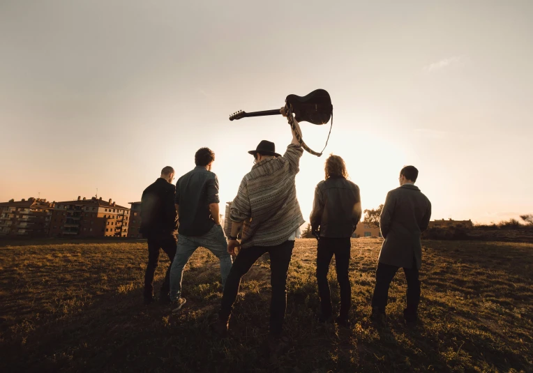 several people standing in the grass with a guitar