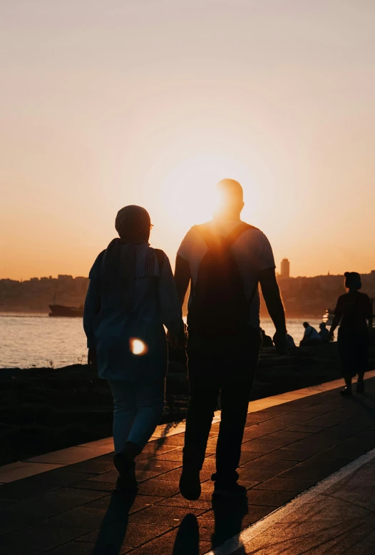 two people walking by the water at sunset