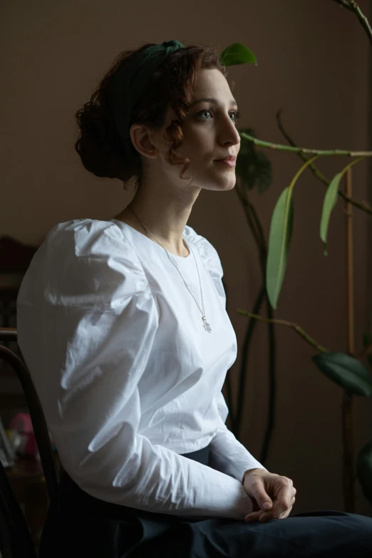 a woman is sitting down by a plant