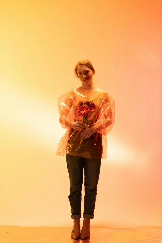 woman standing in an orange light, holding a clear bag