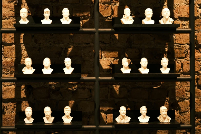 a wall full of statues of men sitting behind bars