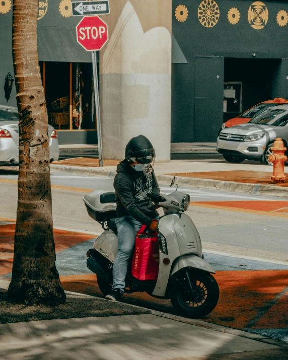a person riding a moped with a red bag on the back