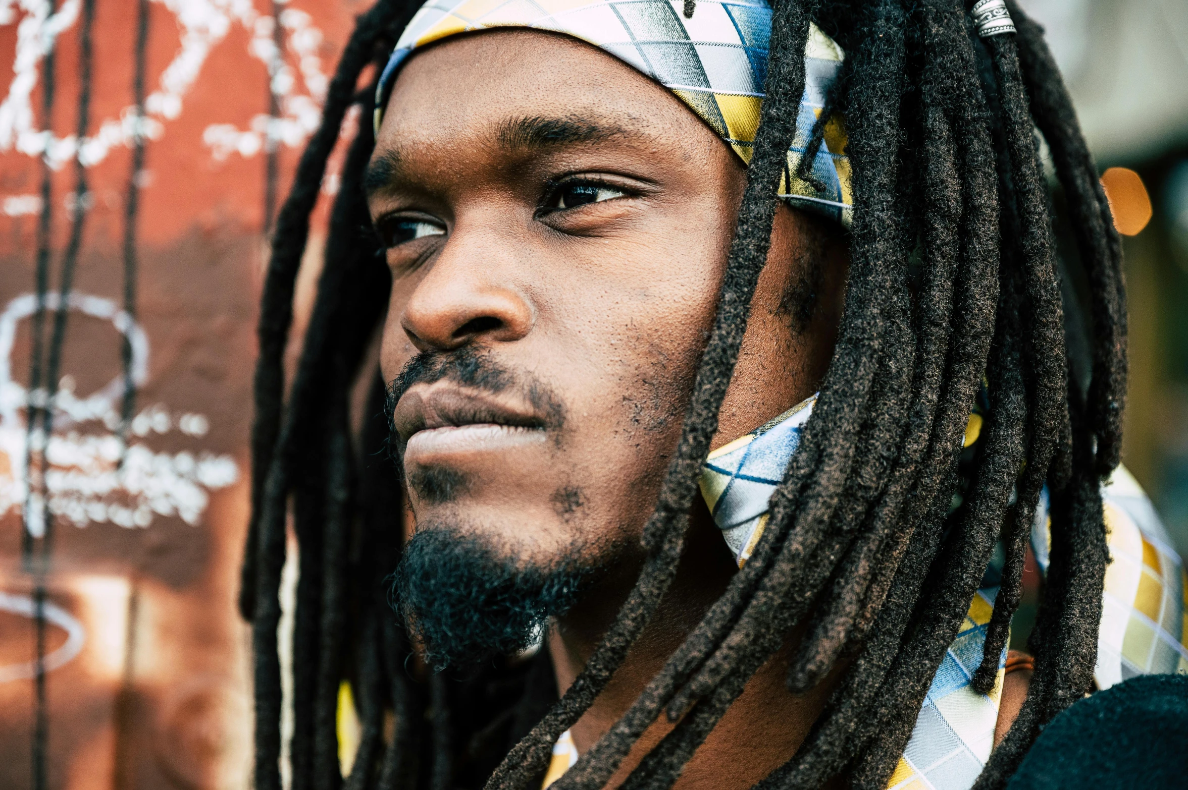 a man with dreadlocks on standing next to graffiti