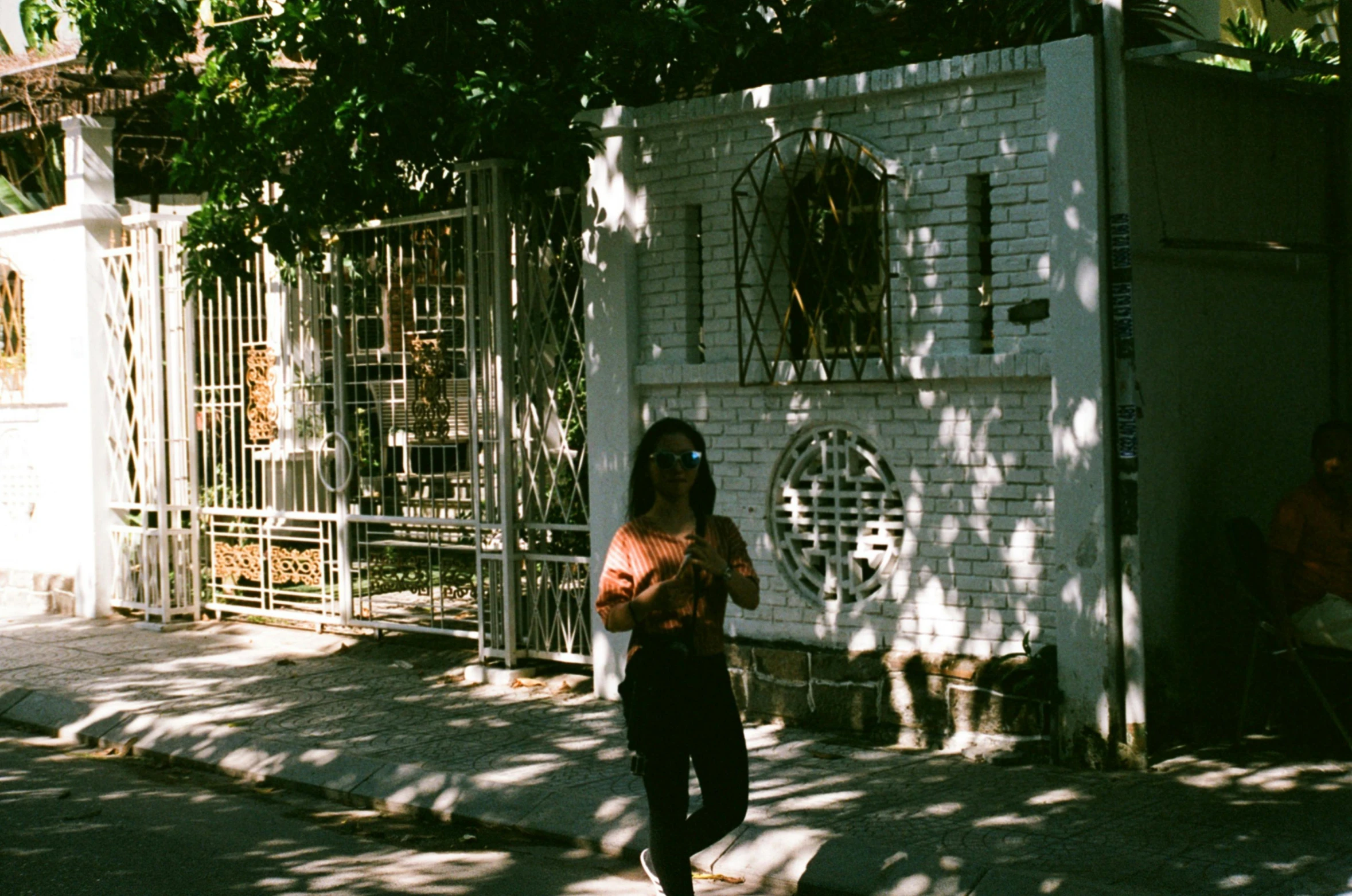 a woman standing next to a white wall and gate