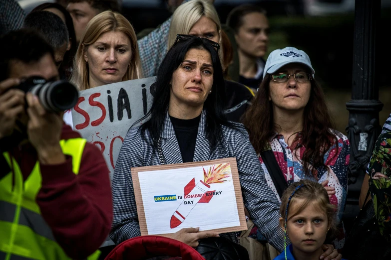 a woman holding a framed sign in front of a crowd