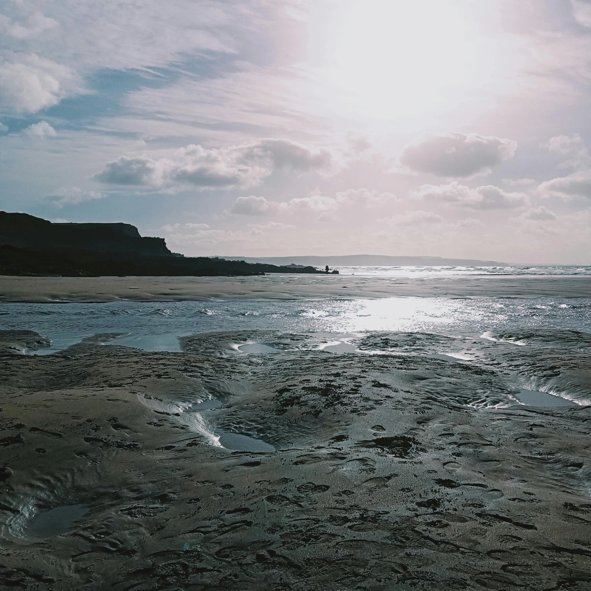 a beach area with water, sky and rocks