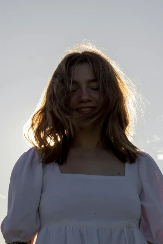 woman in white dress smiling as she stands outdoors