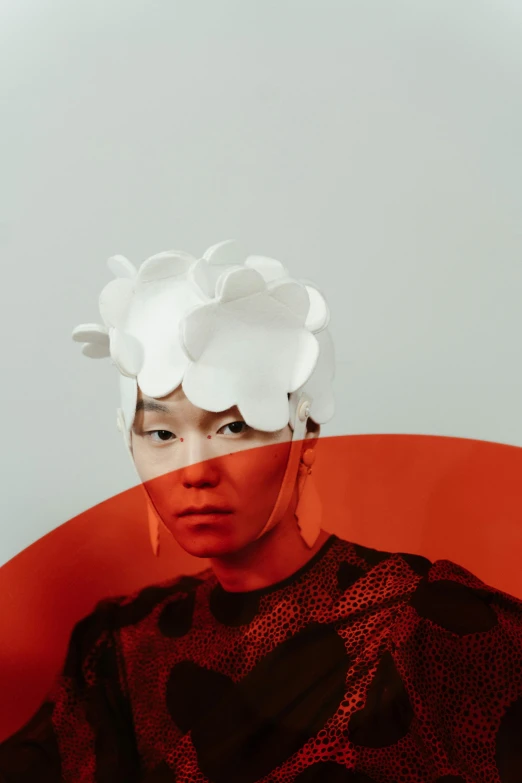 a girl sitting in a chair with some paper flowers on her head