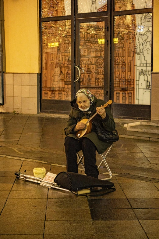 the woman is sitting down playing the guitar