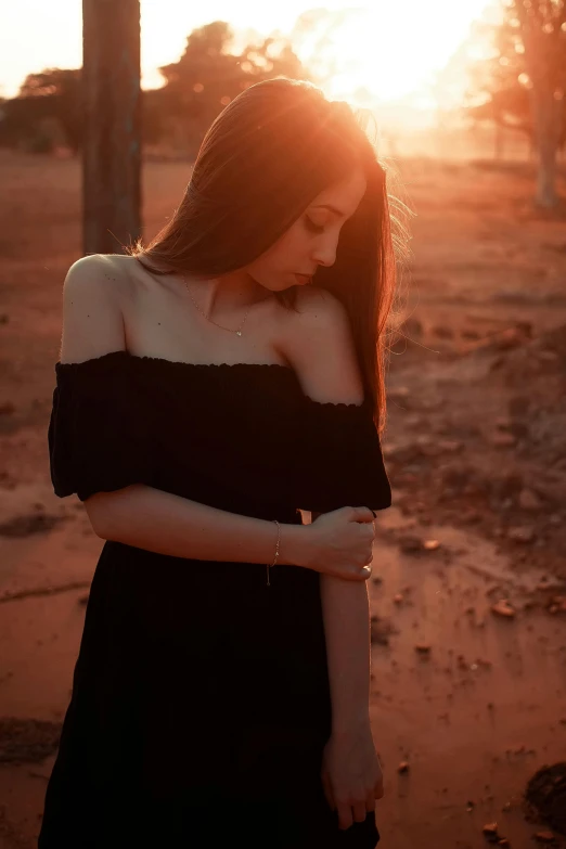 a beautiful young woman standing on a dirt road