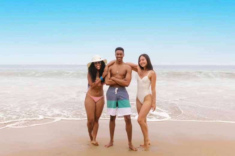 four friends smiling at the ocean with a body suit