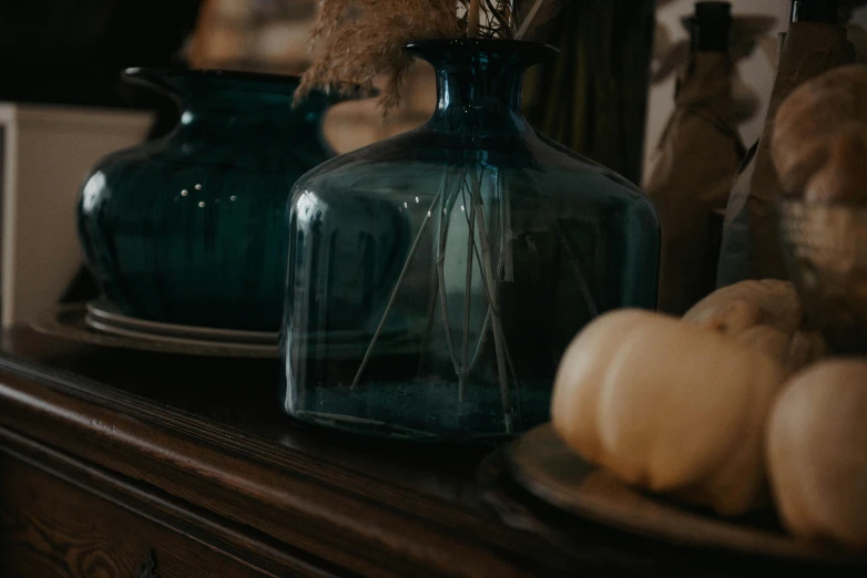 a blue vase filled with dried flowers and oranges