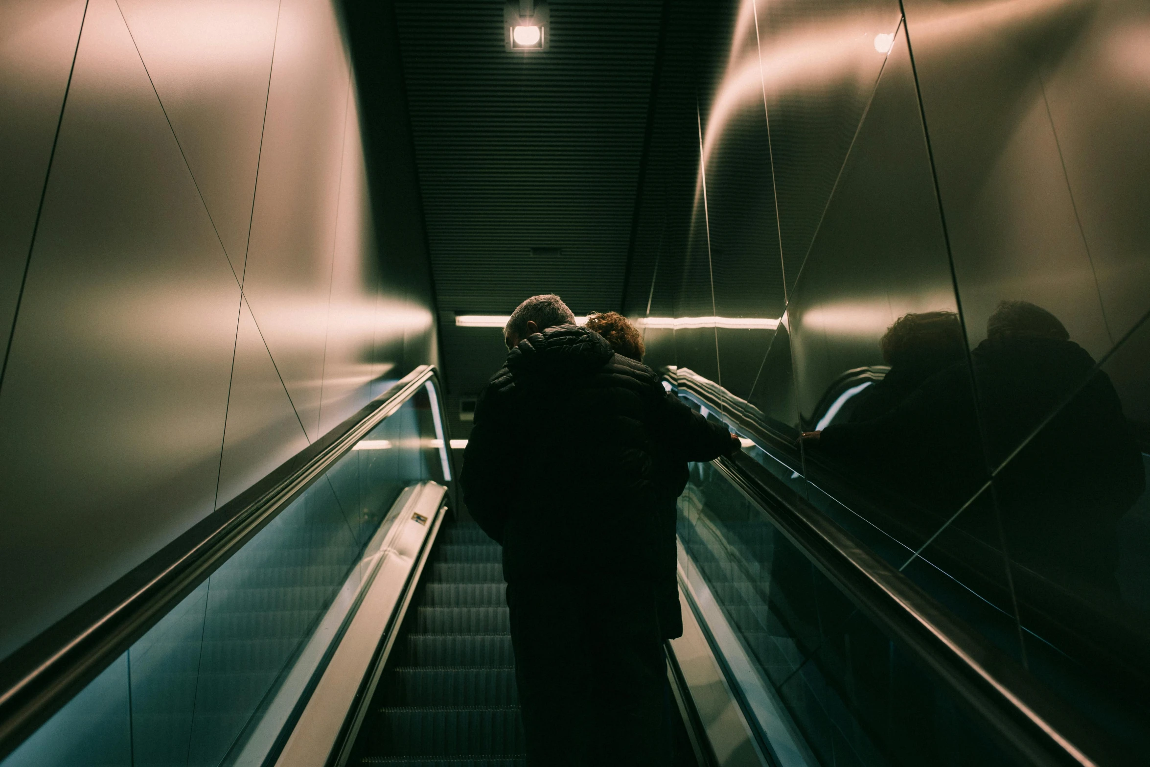 woman with backpack riding an escalator at night