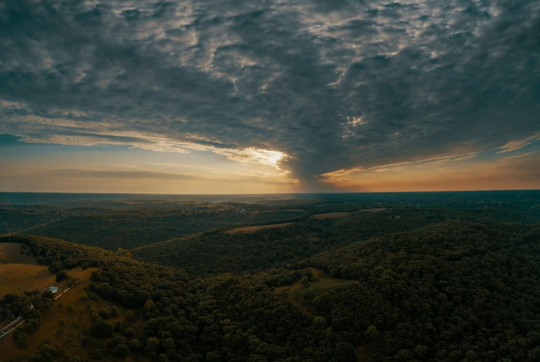 the sun peeks above the rolling hills in the distance