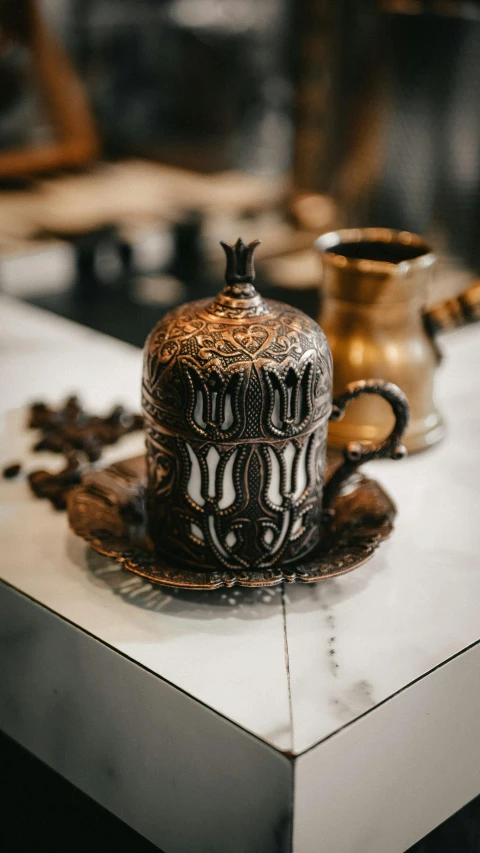 a golden tea pot with a gold saucer on top of it