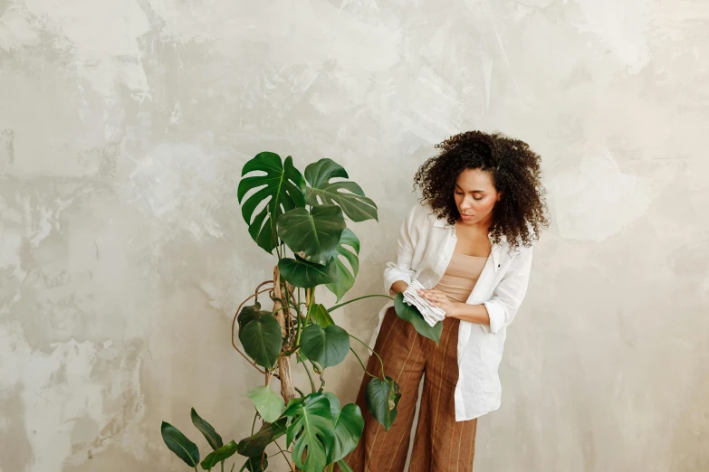 a girl leaning on a wall next to a potted plant