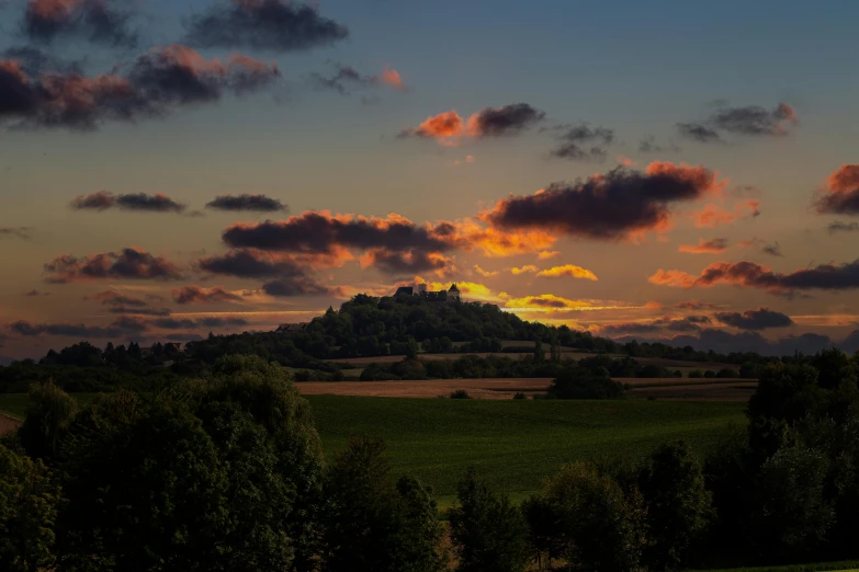 a landscape with trees and an orange sky