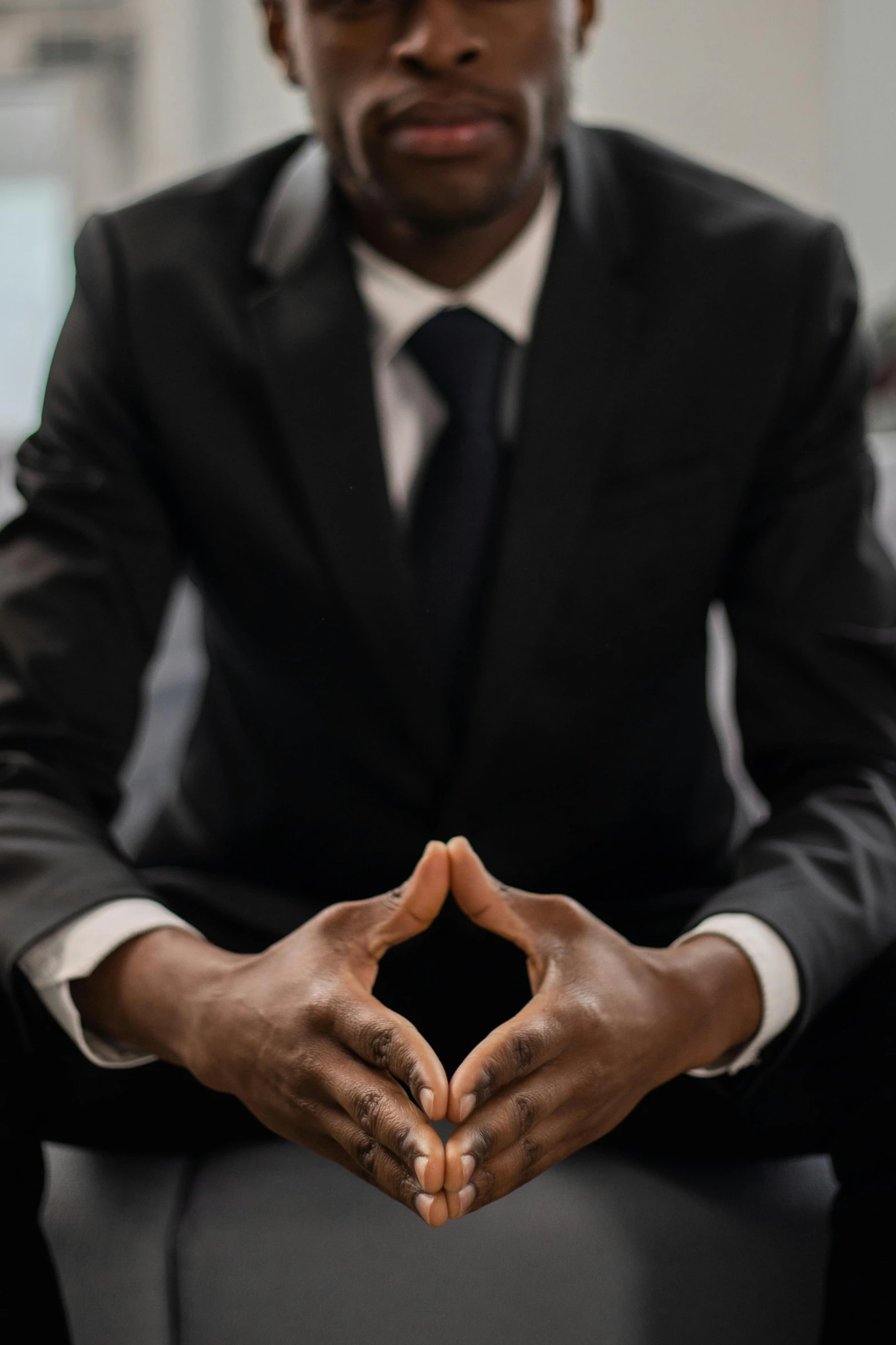 a man in a suit sitting in a chair making a heart