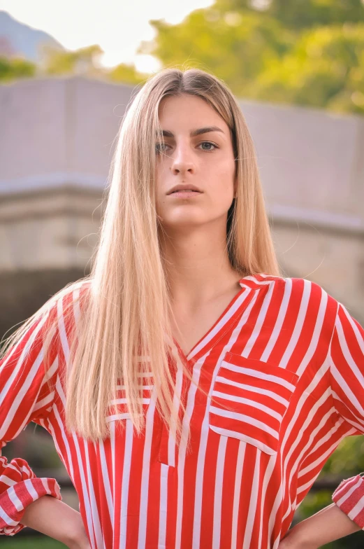 an attractive woman standing on a bridge wearing a red and white striped shirt