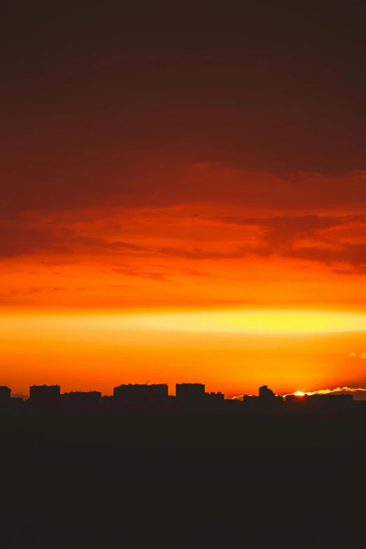 silhouetted buildings and a setting sun are seen