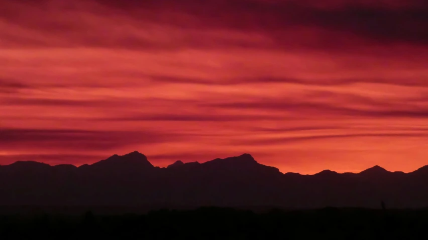 a group of mountains in the distance with a red sky