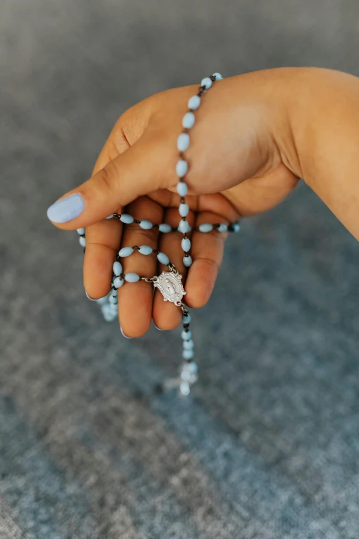 a hand holding rosary with other beads on the wrist