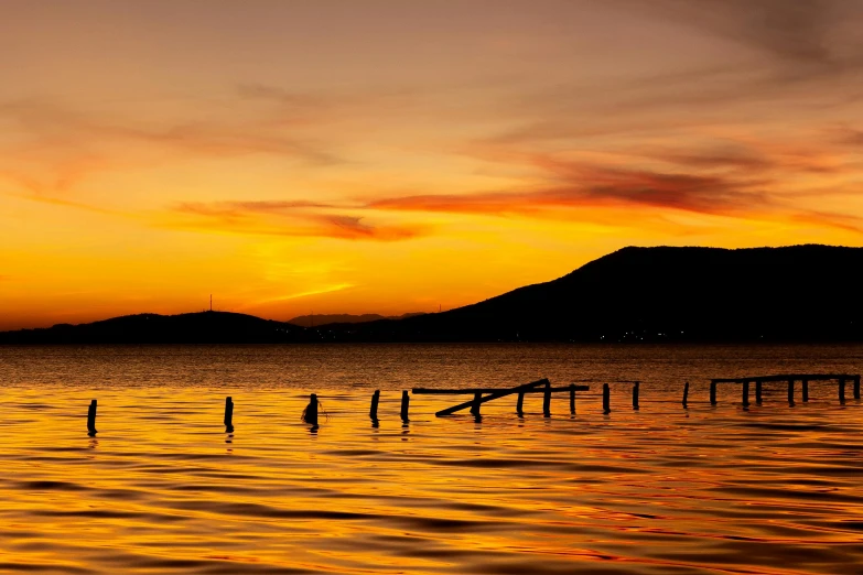 a beautiful sunrise above the water with a row boat in the foreground