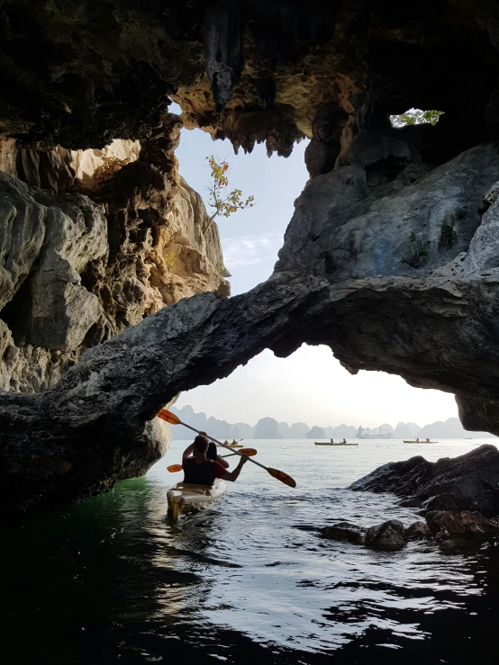 a man in a canoe is going through a cave entrance