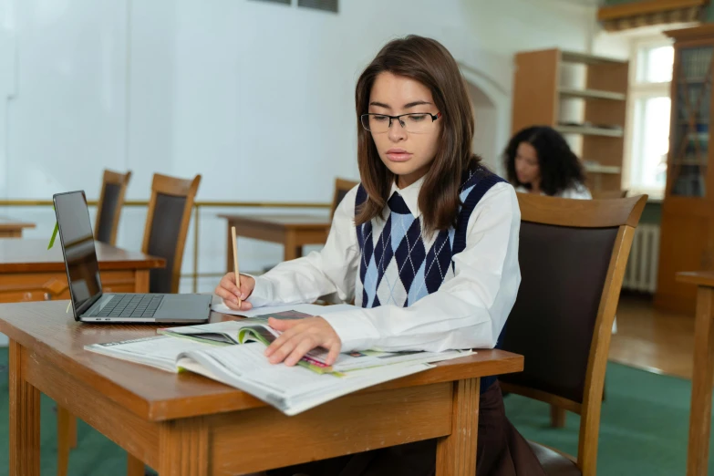 girl sitting at desk in liry with laptop computer