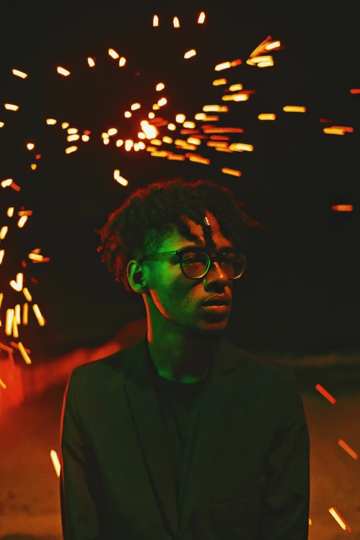 a man with dark hair in glasses and a blazer and confetti