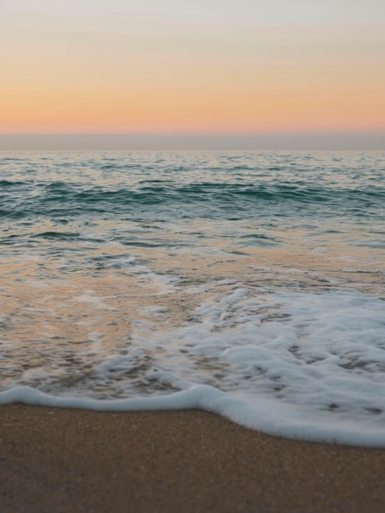 the shore line at sunset with wave coming in and onto it