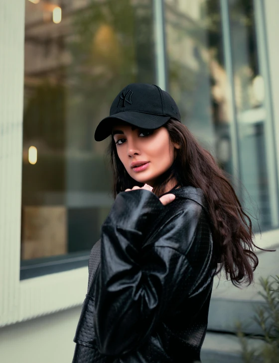 a woman wearing a black hat posing in front of windows