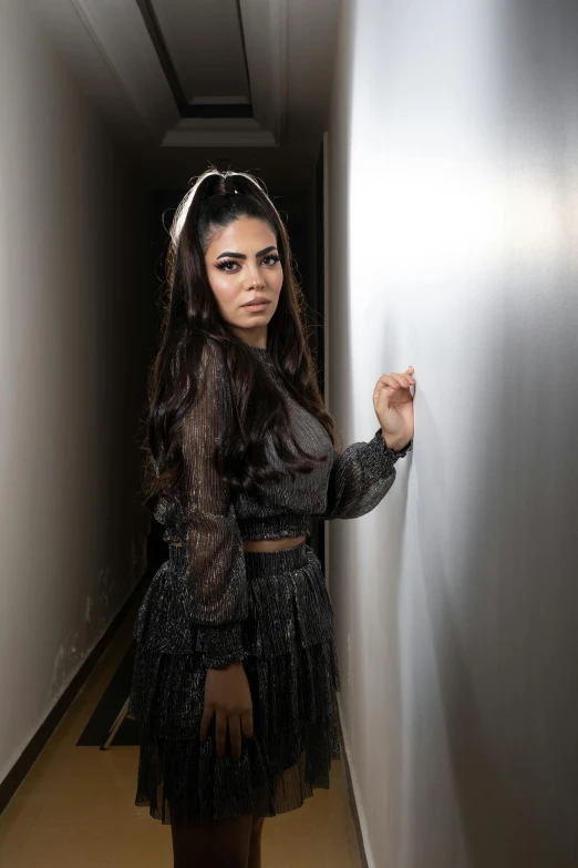 a woman leaning against a wall in an empty corridor